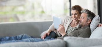 Couple sur un canapé en train de regarder une tablette