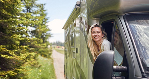 Zwei lächelnde Personen in einem Wohnmobil, bereit für eine Reise.